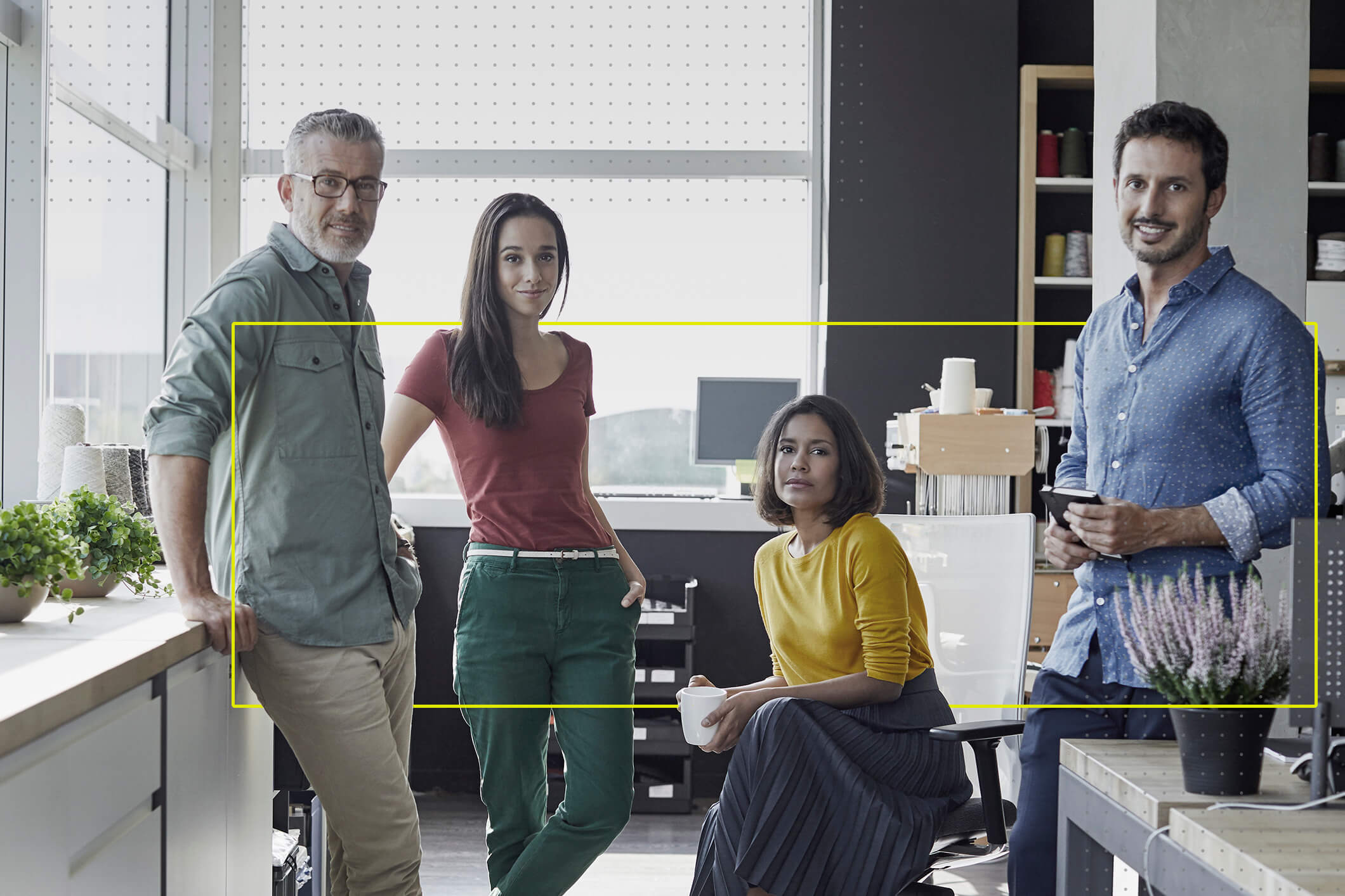 Retrato de 4 personas, 2 hombres y dos mujeres viendo a la cámara en una oficina de trabajo. 